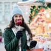 Der Bratapfel gilt als Klassiker auf dem Weihnachtsmarkt Frau isst einen Bratapfel auf dem Weihnachtsmarkt