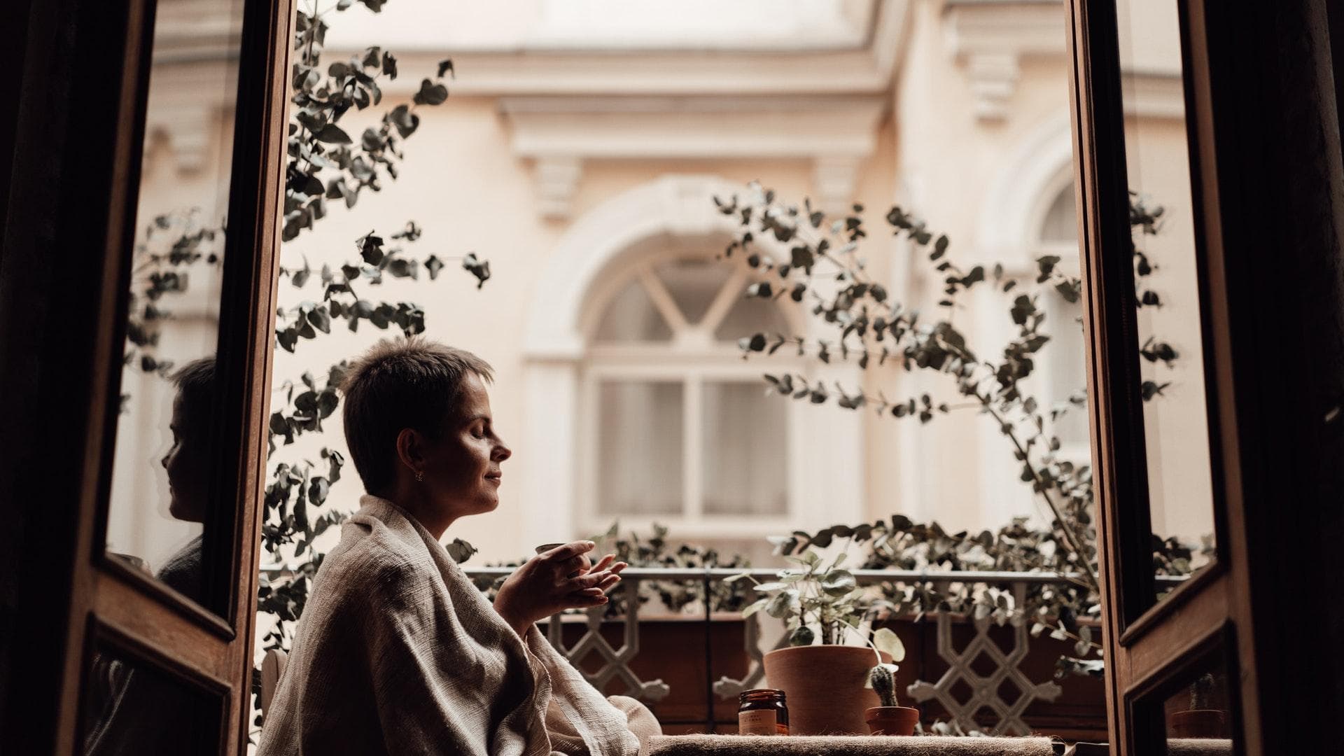 Mit den richtigen Kniffen wirkt selbst der kleinste Balkon größer Frau sitzt auf einem kleinen Balkon