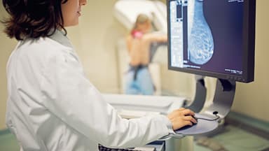 Mammographie Eine Gynäkologin schaut sich das Bild einer Brust an, die gerade mithilfe einer Mammographie untersucht wird