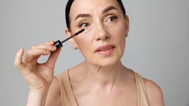 Mit diesem Mascara-Trick können Sie Schlupflider abmildern Frau trägt mit dem Mascara-Trick für Schlupflider Wimperntusche auf
