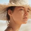 Beim Auftragen von Sonnencreme unter Make-up gibt es ein paar Dinge zu beachten Frau mit Sonnencreme unter Make-up