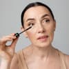 Mit diesem Mascara-Trick können Sie Schlupflider abmildern Frau trägt mit dem Mascara-Trick für Schlupflider Wimperntusche auf