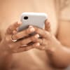 Nicht nur Stars, auch normale Menschen werden immer öfter Opfer von Deepfakes Frau schaut auf ihr Smartphone