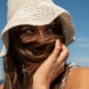 Französinnen wissen, wie man gut durch heiße Tage kommt Frau trägt einen Sonnenhut am Strand