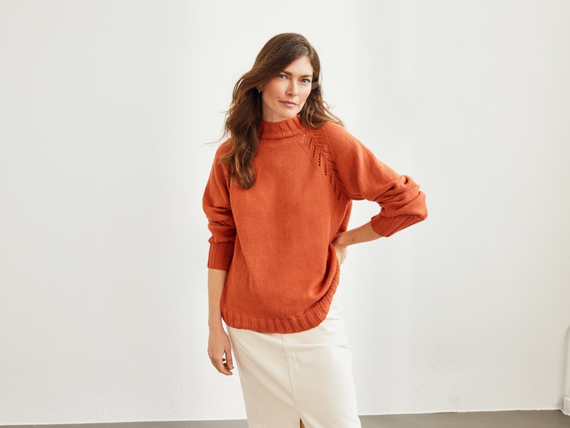 Model in orangefarbenem Pullover mit Lochmuster von Lana Grossa Model in orangefarbenem Pullover mit Lochmuster von Lana Grossa