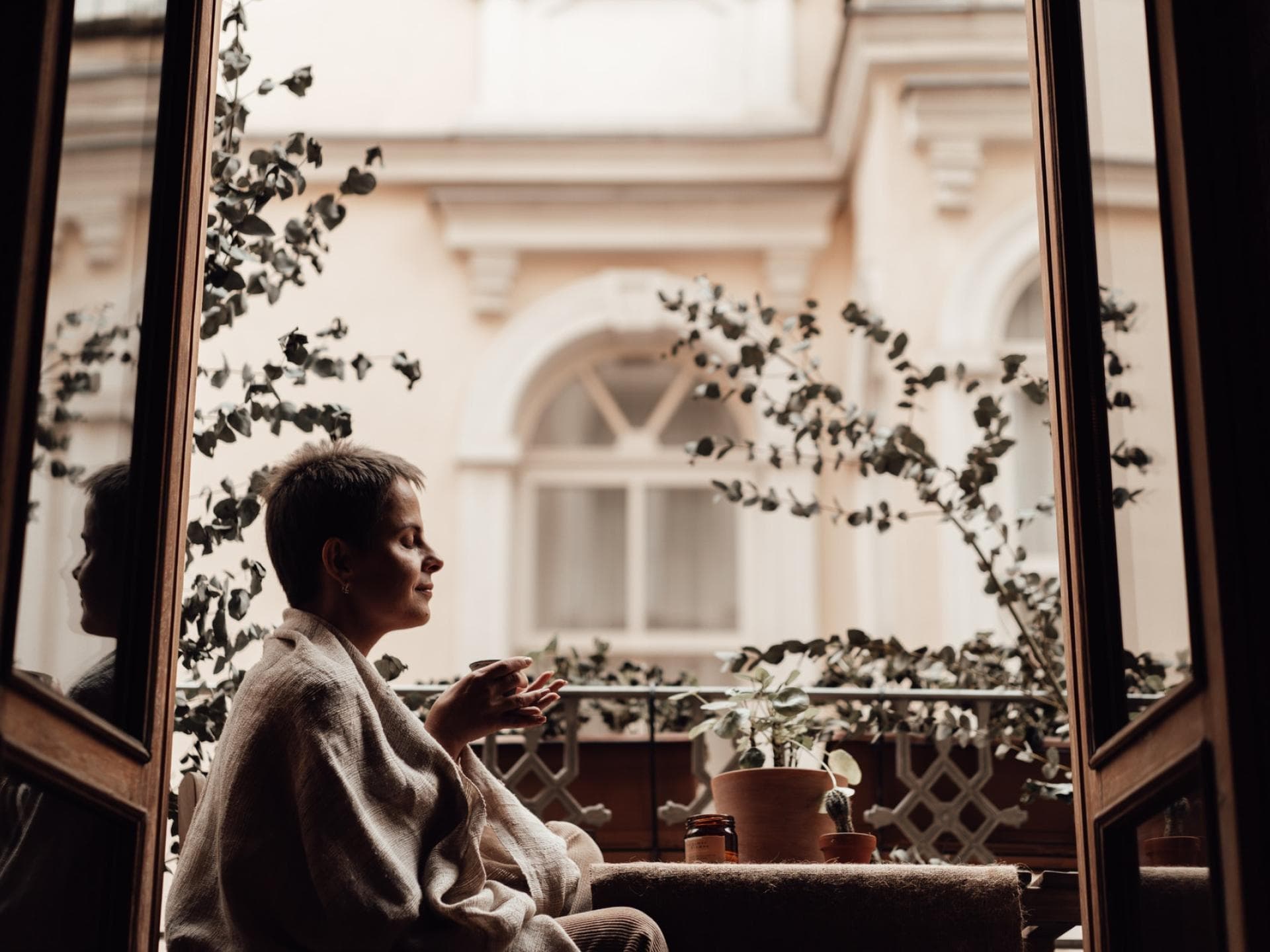 Mit den richtigen Kniffen wirkt selbst der kleinste Balkon größer Frau sitzt auf einem kleinen Balkon