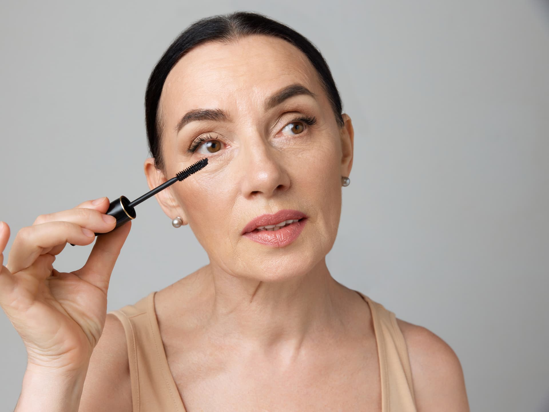 Mit diesem Mascara-Trick können Sie Schlupflider abmildern Frau trägt mit dem Mascara-Trick für Schlupflider Wimperntusche auf