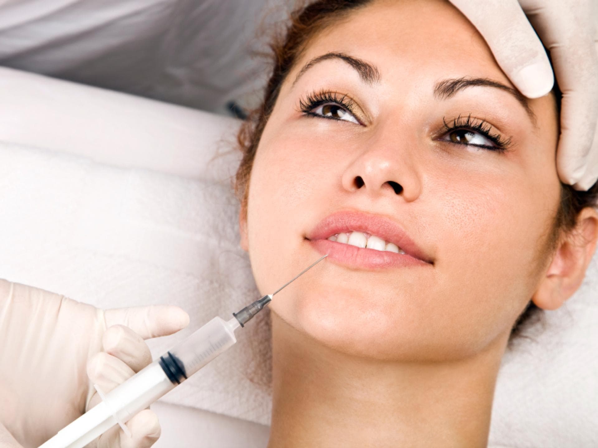 Frau bekommt Botox gespritzt Frau bekommt auf einem Arztstuhl Botox gespritzt