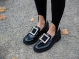 Frau trägt schwarze Loafer mit großer Schnalle. Frau trägt schwarze Loafer mit großer Schnalle.