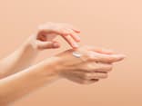 Handcreme mit Sonnenschutz schützt vor vorzeitiger Hautalterung Frau trägt Handcreme mit Sonnenschutz auf ihre Hände auf