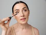 Mit diesem Mascara-Trick können Sie Schlupflider abmildern Frau trägt mit dem Mascara-Trick für Schlupflider Wimperntusche auf